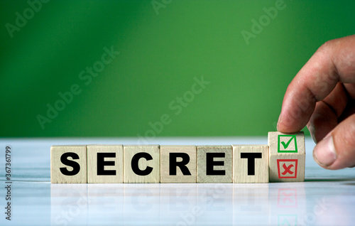 hand turns the wooden cube and changes the word SECRET
