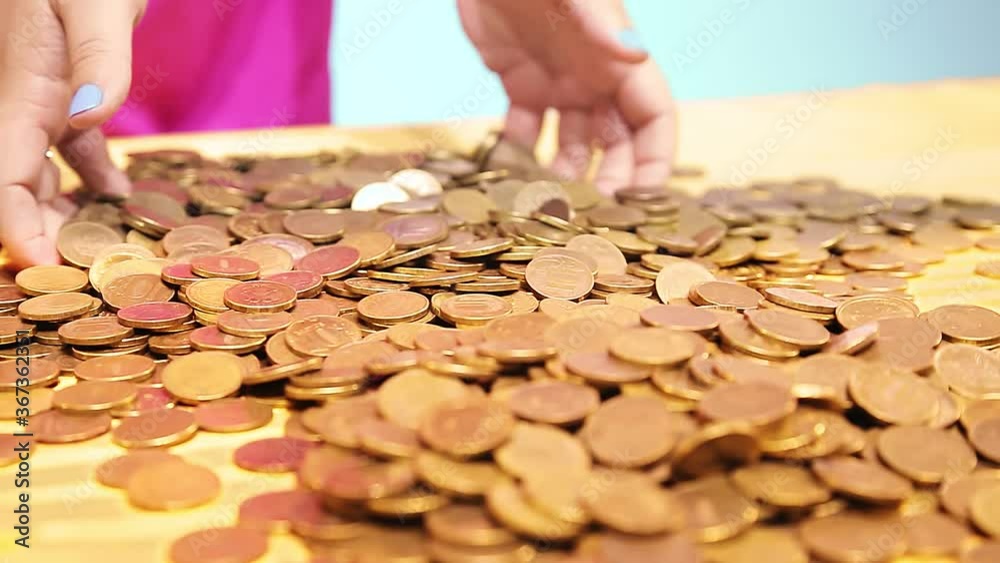 The woman pours coins scattered on the table in her hands. Overall plan The woman pours coins scattered on the table in her hands. Overall plan