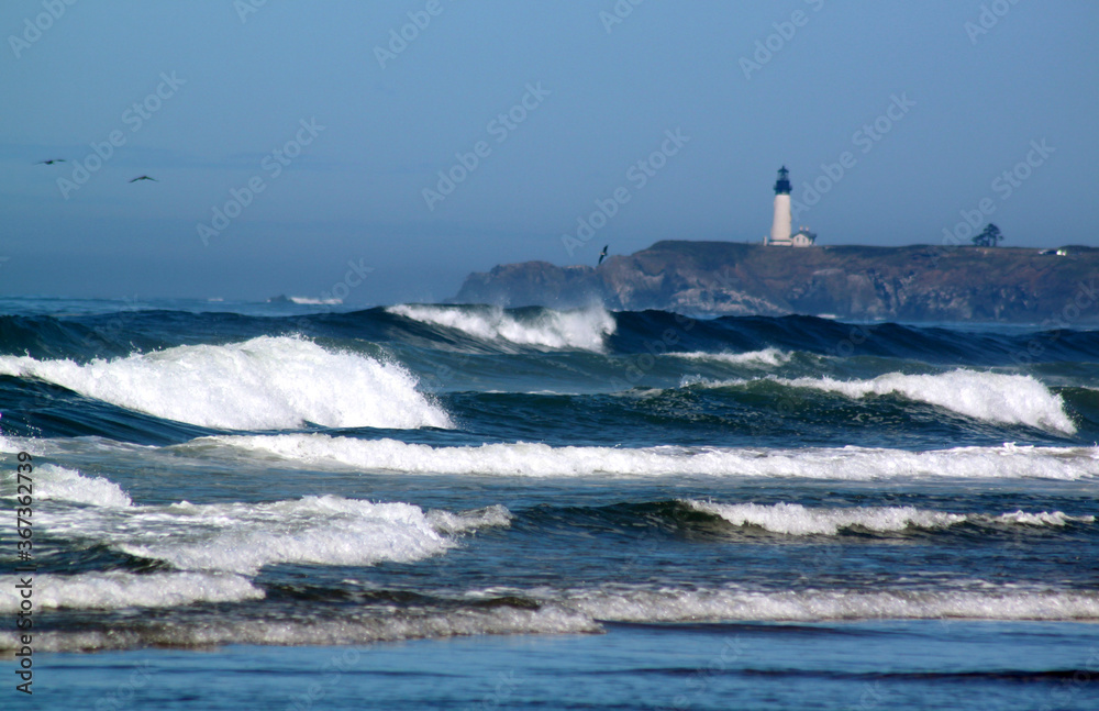 Waves crashing on shore near lighthouse on Pacific coastline