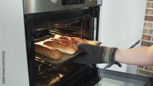 Baker takes hot bread out of the oven.