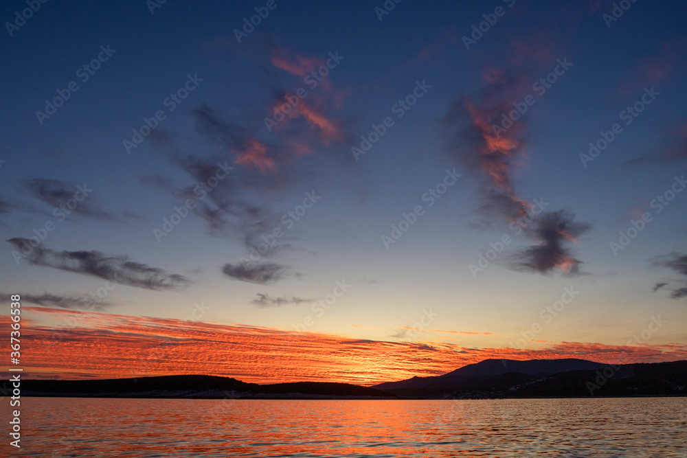 Beautiful orange red clouds on colorful sunset on Adriatic sea, island Vis, Croatia