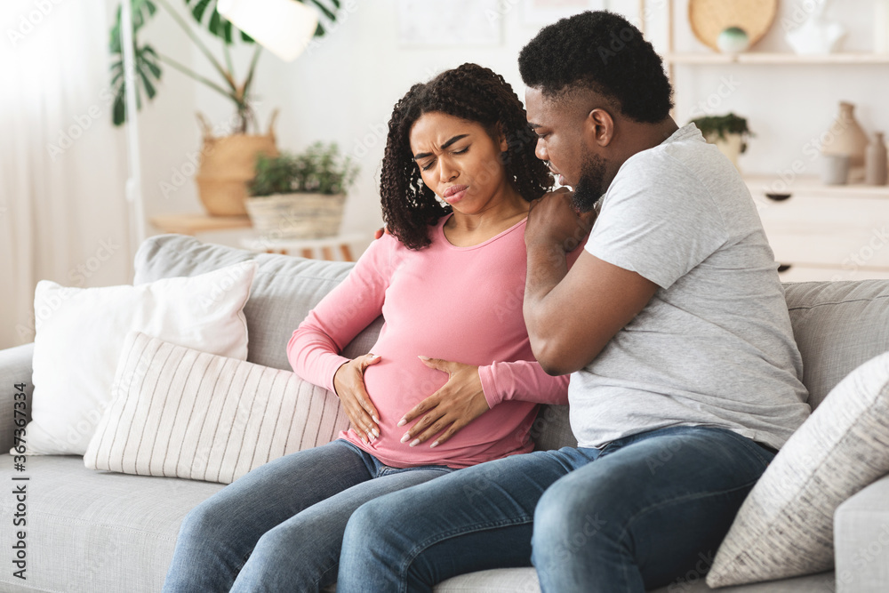 Attentive african husband supporting his pregnant wife in pain