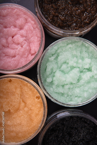 round jars with colored substance, top view, body scrub in different colors,