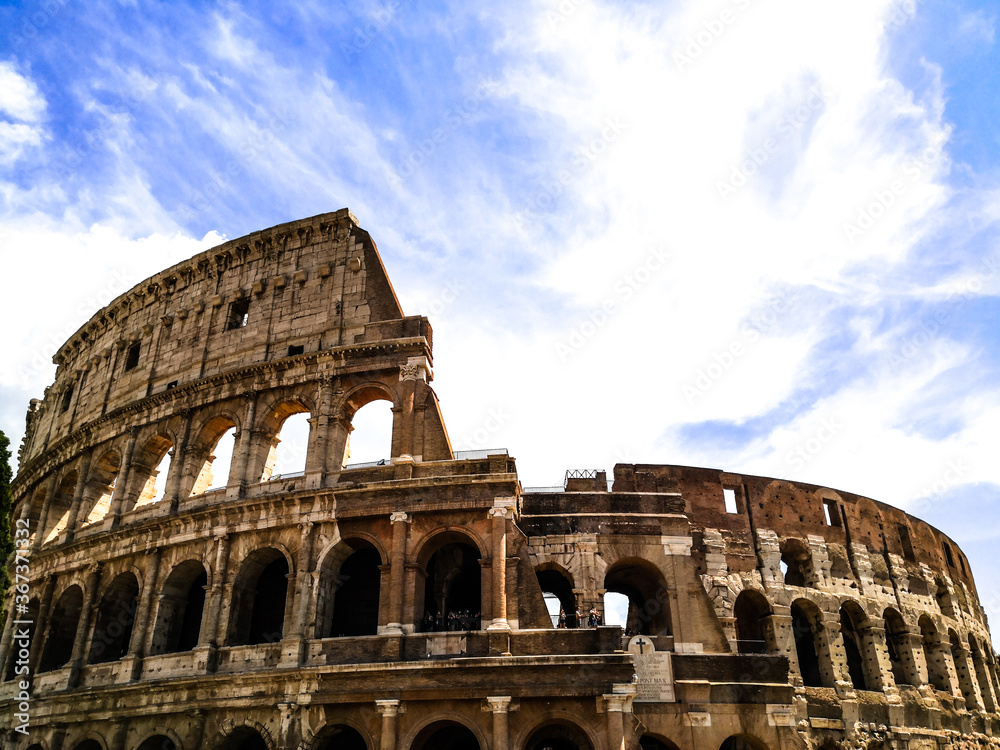 Photo of the Colosseum in Rome dominated by clouds in a blue sky