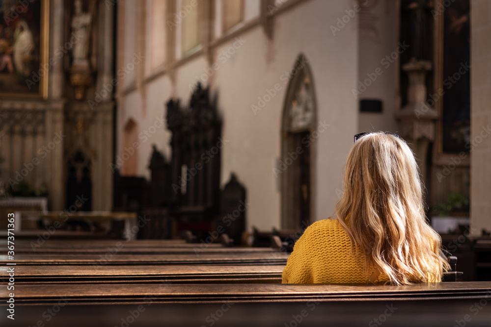 Woman sitting on pew and praying in empty church. Catholic religion at European culture Woman sitting on pew and praying in empty church. Catholic religion at European culture