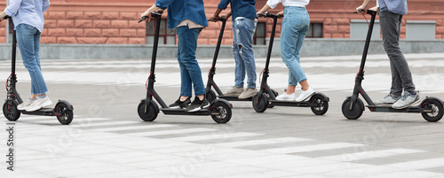 Five friends having ride on motorized kick scooters photo