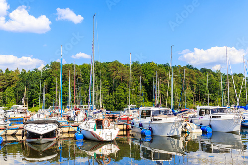 Reflections of sailing boats on lake shore in Ruciane-Nida town marina at sun...