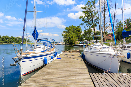 Sailing boats anchoring at pier of Lake Beldany in port Wierzba on summer sun...