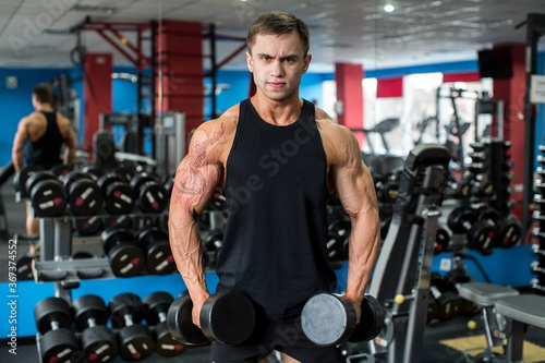 .Muscular man working out in gym doing exercises with dumbbells, bodybuilder male