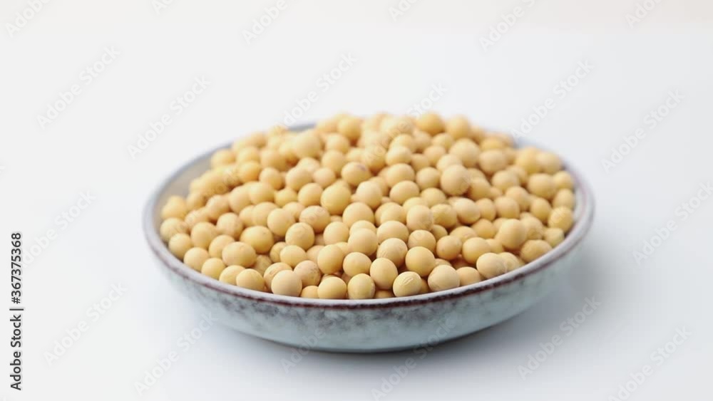 Rotating of soy seeds in ceramic plate on white background. Side view, close up. Rotating of soy seeds in ceramic plate on white background. Side view, close up.