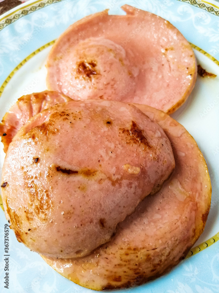 Obraz premium Sliced fried sausage mugs on a plate.