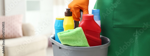 Closeup view of woman with detergents in living room, banner design. Cleaning service