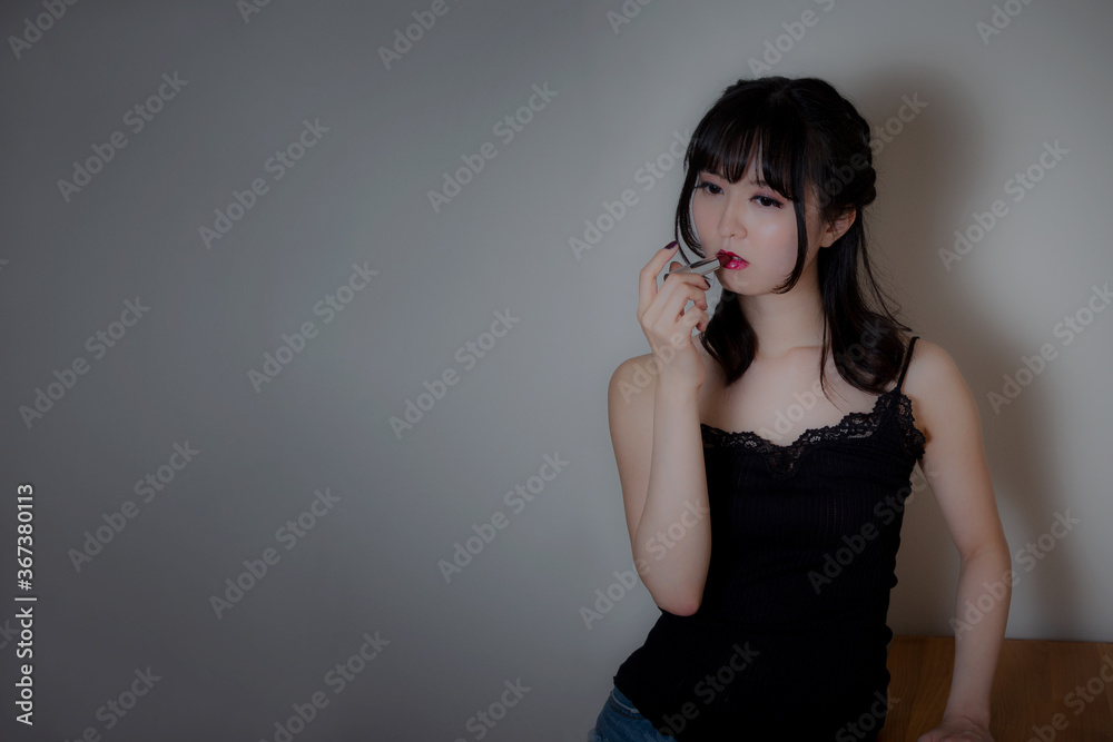 Fototapeta premium 濃い口紅をつけるキャミソール姿の女性