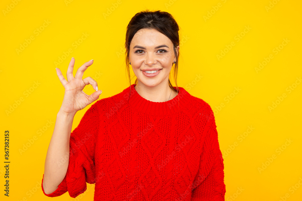 Woman in the bright colored sweater showing ok sign Woman in the bright colored sweater showing ok sign