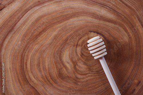 wooden honey dipper lies on a slice of a tree. wooden table. With copy space.