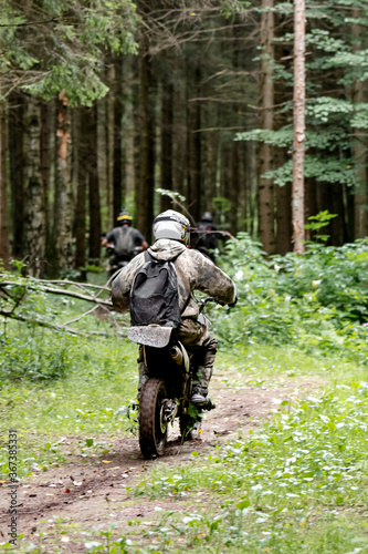 group of motorcyclists in helmets rides on a forest dirt road