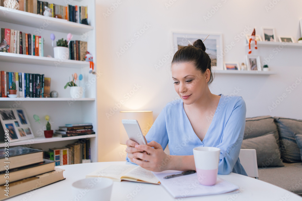 Young woman working at home and using mobile phone Young woman working at home and using mobile phone