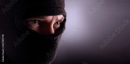 angry man in a balaclava on a dark background. Rebellious protester in a mask