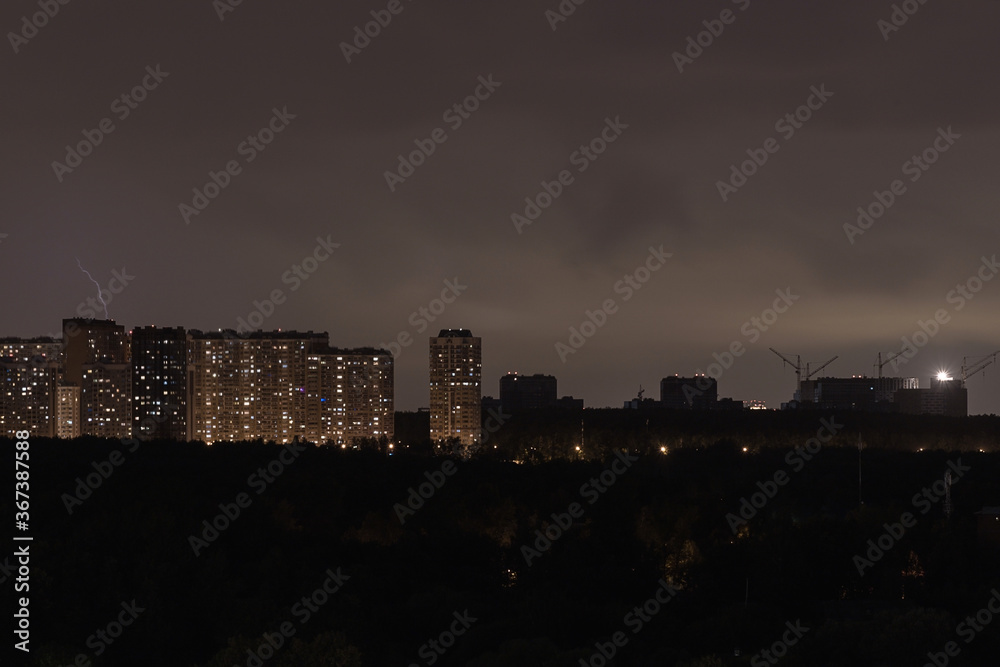 Silhouette of the night city. Lightning over the city. Storm over a residential area. lightning flashes on the horizon.