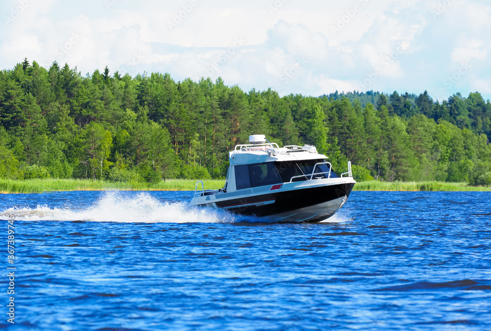 Naklejka premium Motor boat on the lake, coniferous forest in the background