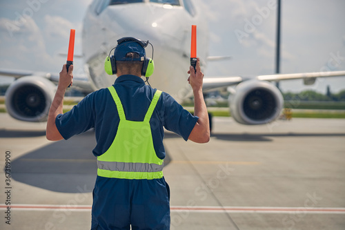 Marshaller in the safety overalls signaling the pilot photo