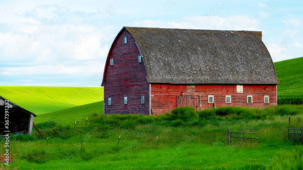 Classic red barn with green rolling hills