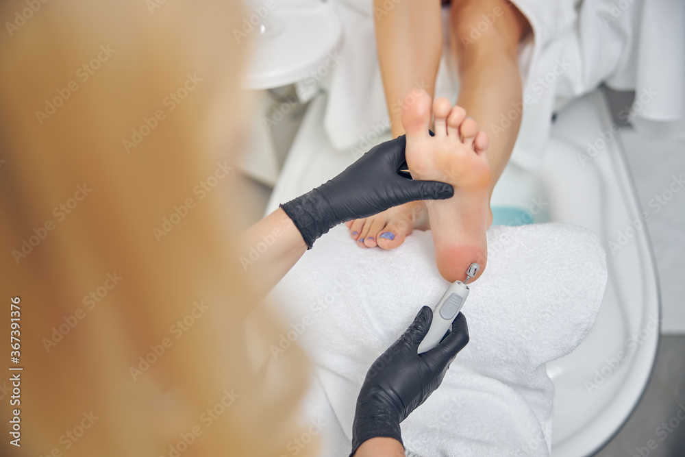 Female beautician doing hardware pedicure for client
