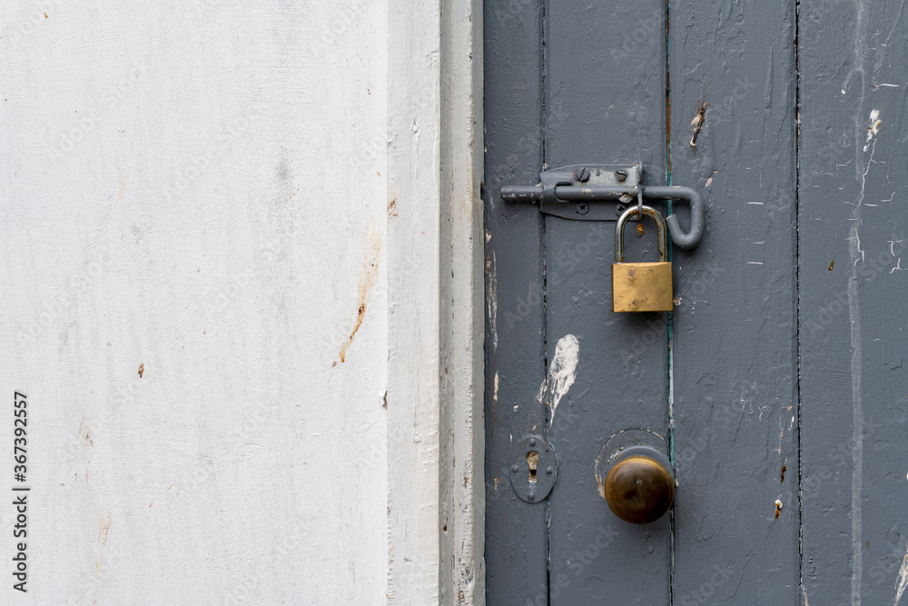 Painted old wooden door bolted shut and locked with a padlock Painted old wooden door bolted shut and locked with a padlock