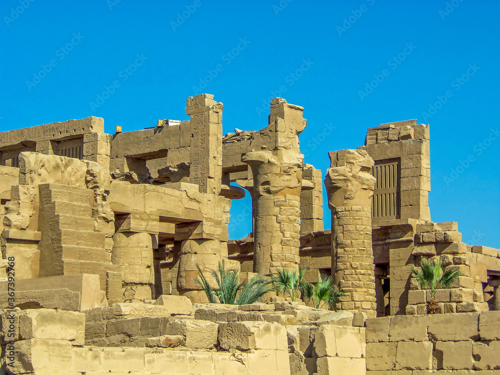Ruined pillars of the temple complex at Karnak near Luxor, Egypt silhouetted against a blue sky in summer
