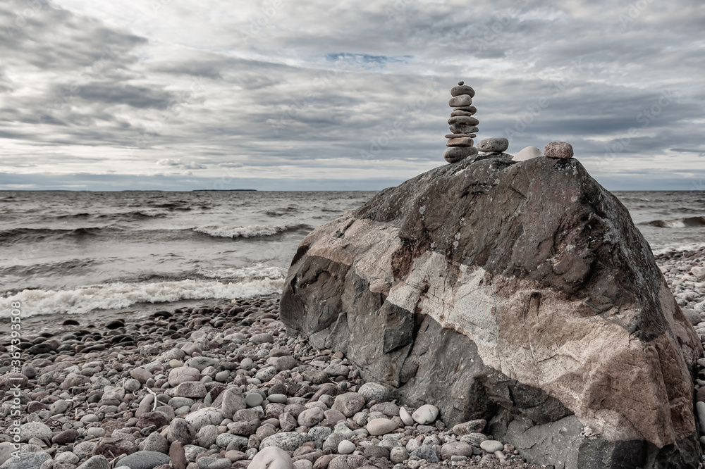 Fototapeta premium Beautiful natural stones that are stacked on a large rock by the Swedish Baltic Sea on an empty pebble beach