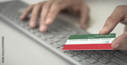 Man pays online with plastic bank card with printed flag of Hungary. Fictional numbers