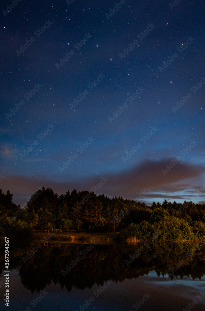 Evening landscape: Ursa major constellation  and first stars and a comet Neowise over a forest lake just after sunset. Long exposure night landscape. 