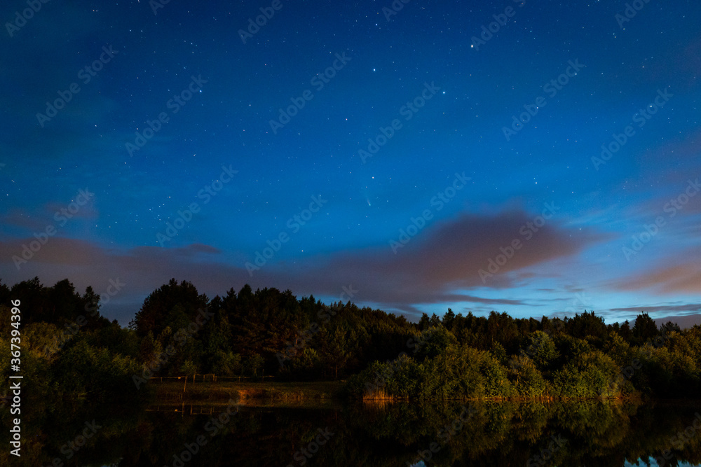 Evening landscape: Ursa major constellation  and first stars and a comet Neowise over a forest lake just after sunset. Long exposure night landscape. 