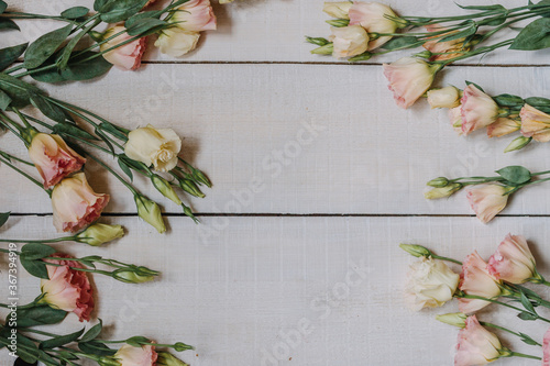 Flower frame made of white and pink eustoms in the style of fine art for an invitation or postcard. Eustoma flowers on a white wooden Board background with space for copying and text in pastel colors. photo