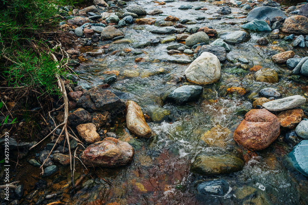 Scenic landscape with awesome motley small river. Picturesque view to beautiful mountain creek with multicolor clay on bottom. Amazing vivid scenery with mountain stream. Nature background with brook. Scenic landscape with awesome motley small river. Picturesque view to beautiful mountain creek with multicolor clay on bottom. Amazing vivid scenery with mountain stream. Nature background with brook.