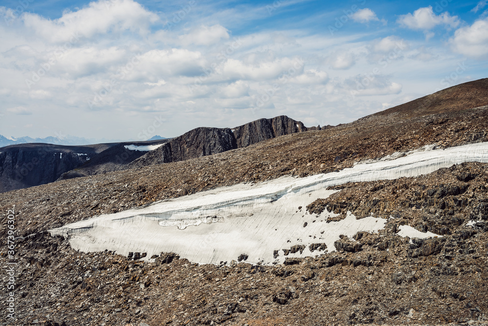 Atmospheric mountain landscape with glacier on rocky hill. Awesome scenery with stony pass with snow in sunlight. Mountain of stones on high altitude. Snow on pass. Beautiful view to highland nature. Atmospheric mountain landscape with glacier on rocky hill. Awesome scenery with stony pass with snow in sunlight. Mountain of stones on high altitude. Snow on pass. Beautiful view to highland nature.