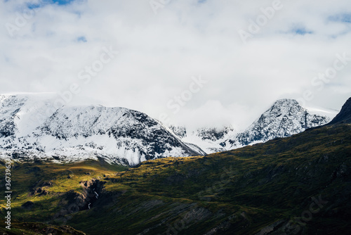 Wonderful view to great mountains with snow on tops and glaciers. Dramatic landscape with snowy mountains under cloudy sky. Atmospheric alpine scenery with snow on rocky mountains in overcast weather.