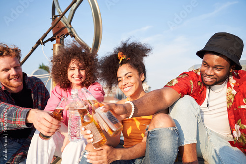 Merry young company celebrating with drinks on roof