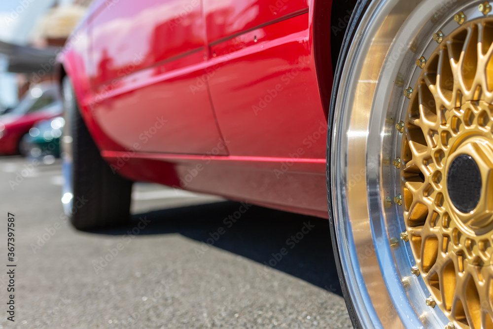Wheel car. Beautiful golden wheel on a background of a sports red car