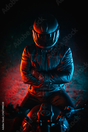 Fotografia biker with black helmet and crossed arms at night and colorful lights