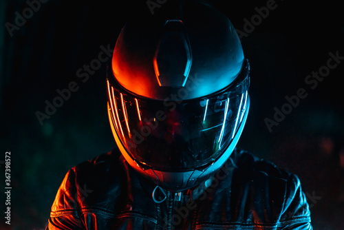 biker with black helmet at night and orange and blue lights