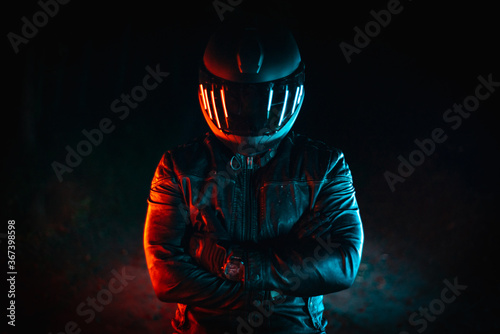 Valokuva motorcyclist with black helmet at night and crossed arms