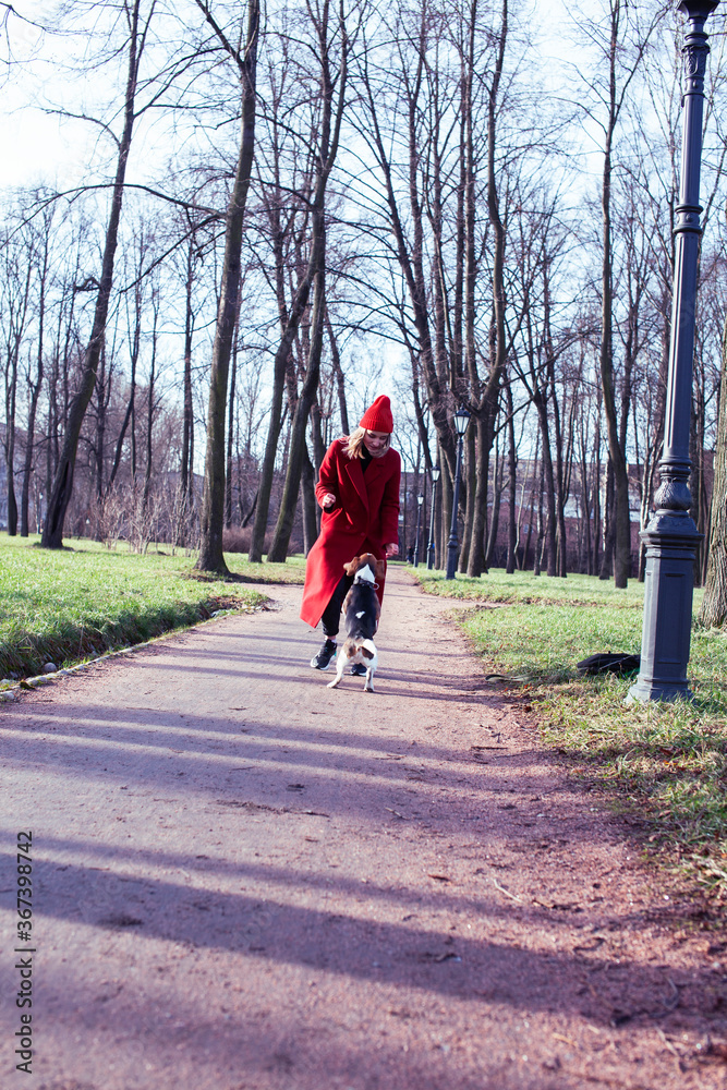 pretty young girl in redd coat playing with dog outside in green park, lifestyle people concept pretty young girl in redd coat playing with dog outside in green park, lifestyle people concept