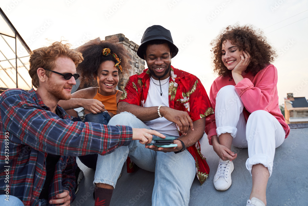 Jolly young company using smartphones together outdoors Jolly young company using smartphones together outdoors