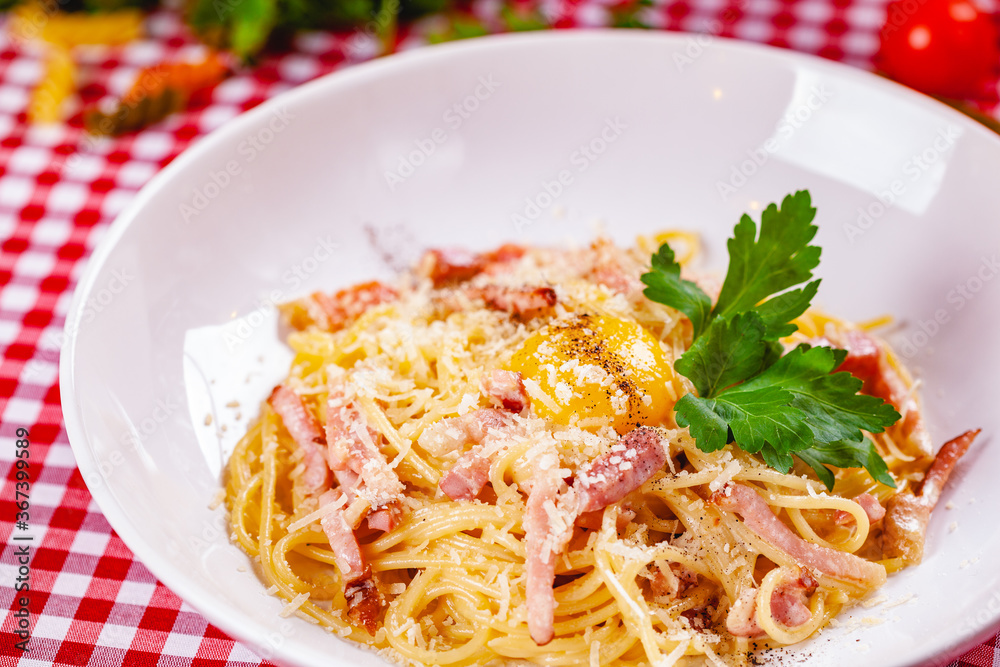 Spaghetti Carbonara with bacon, yolk and cheese on white plate. Close up Spaghetti Carbonara with bacon, yolk and cheese on white plate. Close up
