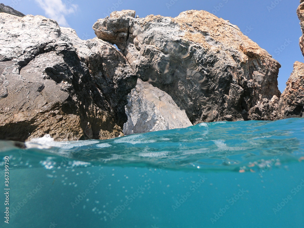 Sea level and underwater ultra wide photo of Lalaria beach, one of the most beautiful in Greece and one that made Skiathos island famous with arch like rock formation, Sporades islands