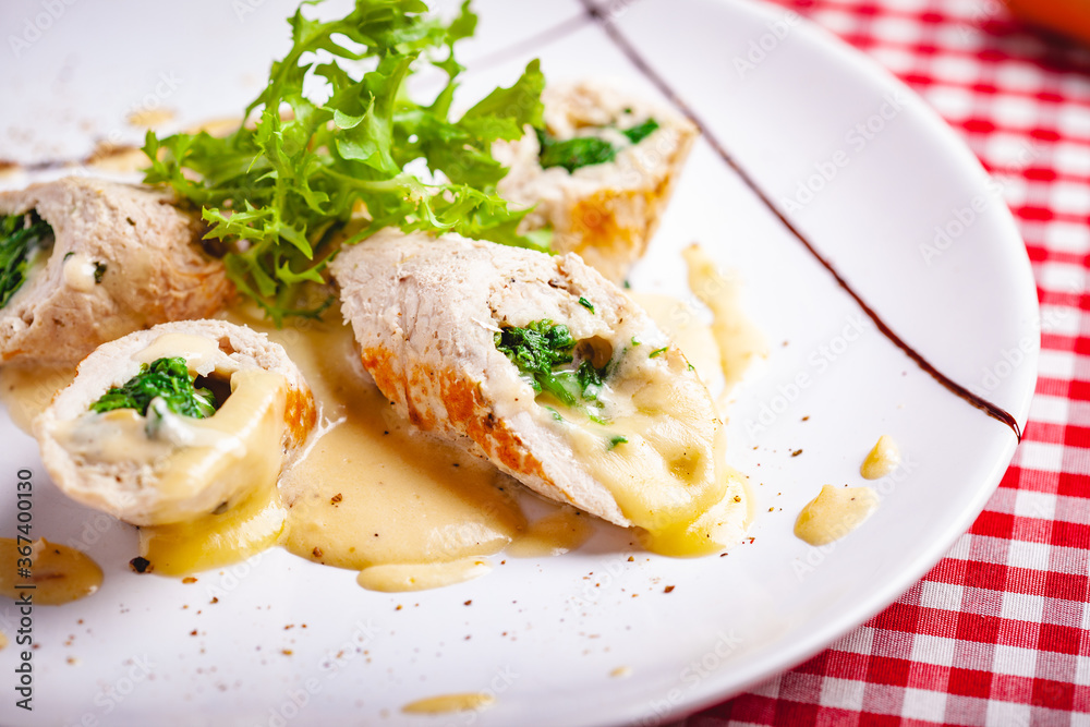 Steamed chicken cutlets stuffed with spinach on white plate. Close up