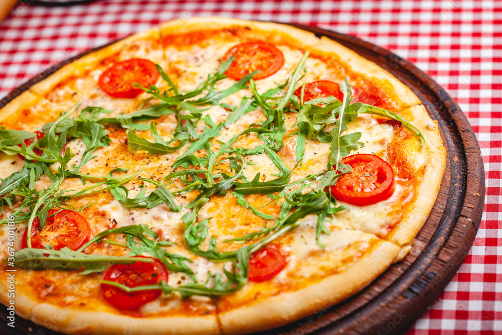 Pizza Margherita (Margarita) with fresh arugula on wooden board. Close up Pizza Margherita (Margarita) with fresh arugula on wooden board. Close up
