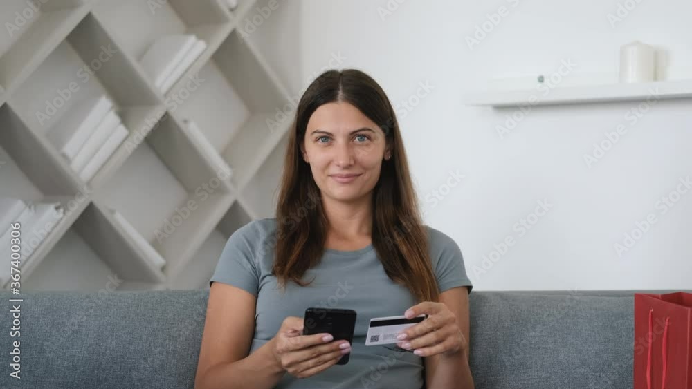 Online shopping, Buying from home, Credit card, Online store. Portrait of a girl who sits on the couch at home and makes an online purchase using the phone Online shopping, Buying from home, Credit card, Online store. Portrait of a girl who sits on the couch at home and makes an online purchase using the phone