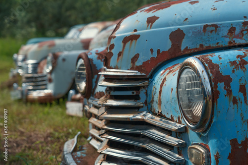 Old retro rusty abandoned cars in green grass.